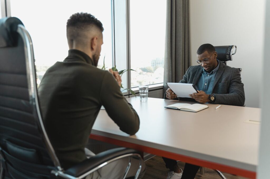 Home A job interview taking place in a modern office setting between two professional men.