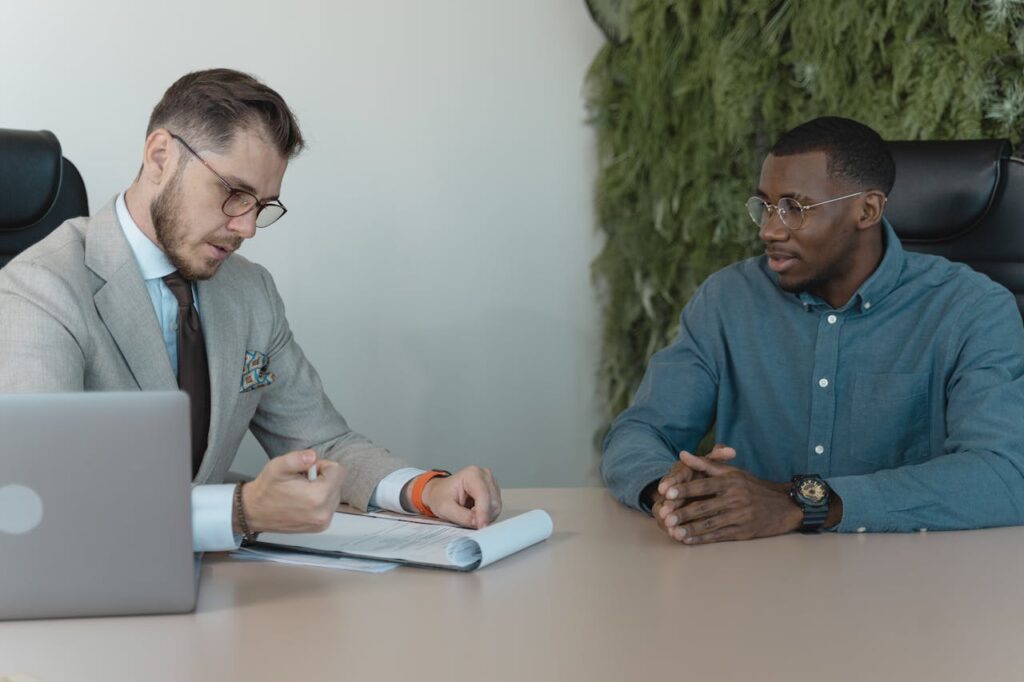 Home A professional job interview between two men in a modern office environment.
